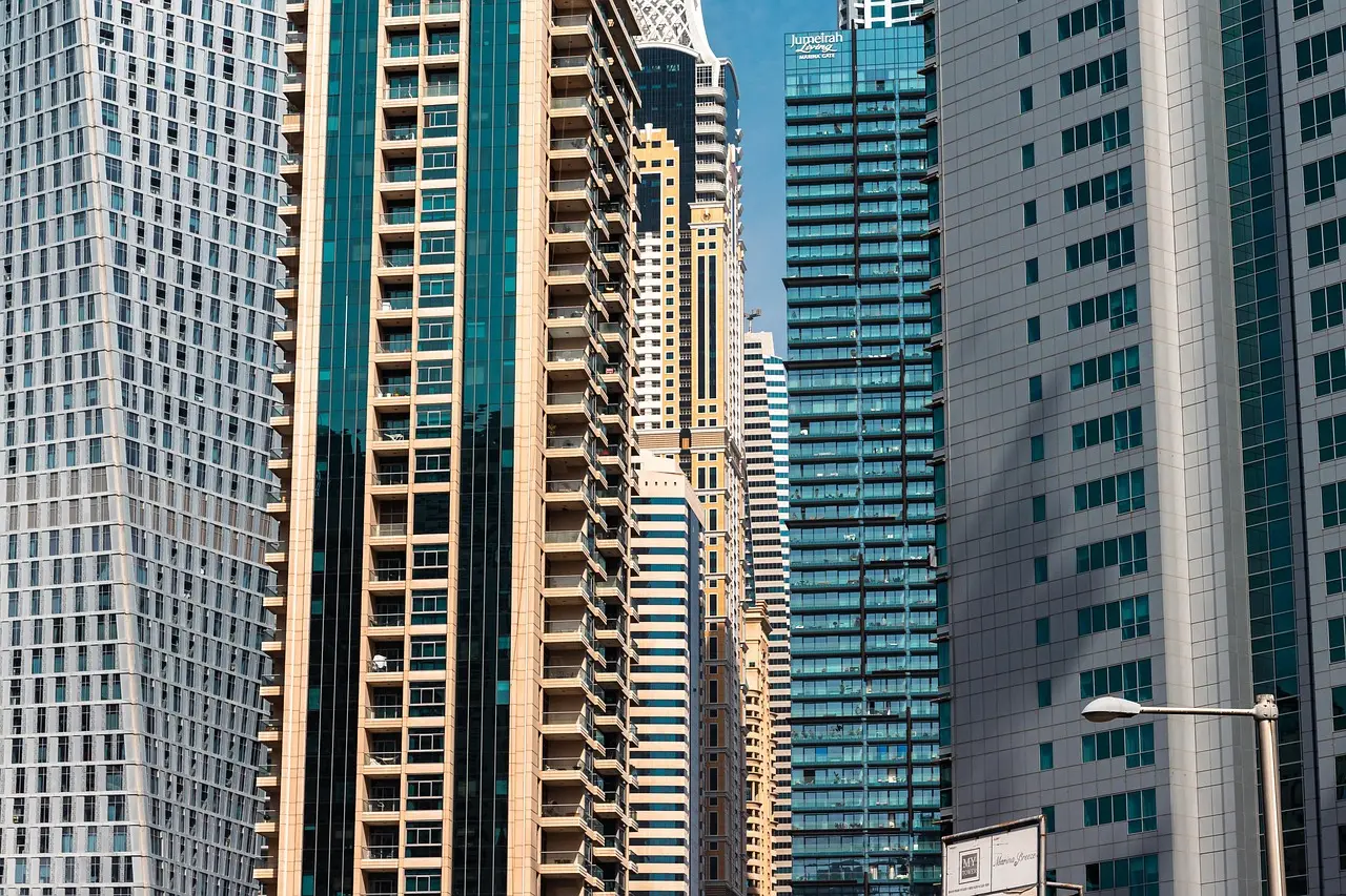 Dense cluster of high-rise residential towers with tiered balconies and glass facades under a clear blue sky in Dubai Marina